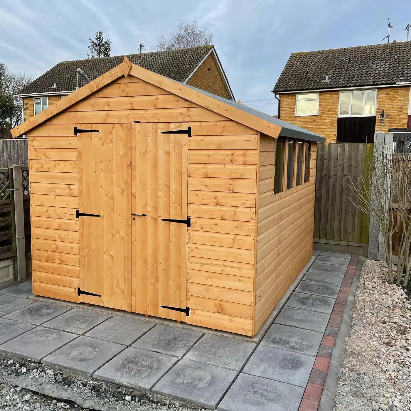 A shed surrounded by grey block paving