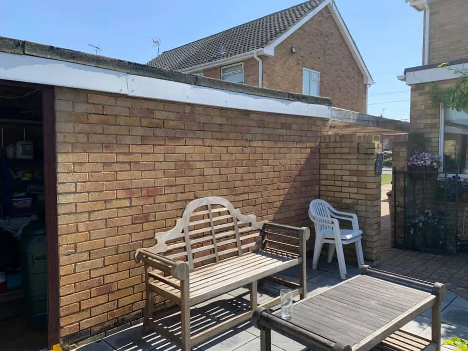 Bench and plastic chair in front of a brick wall